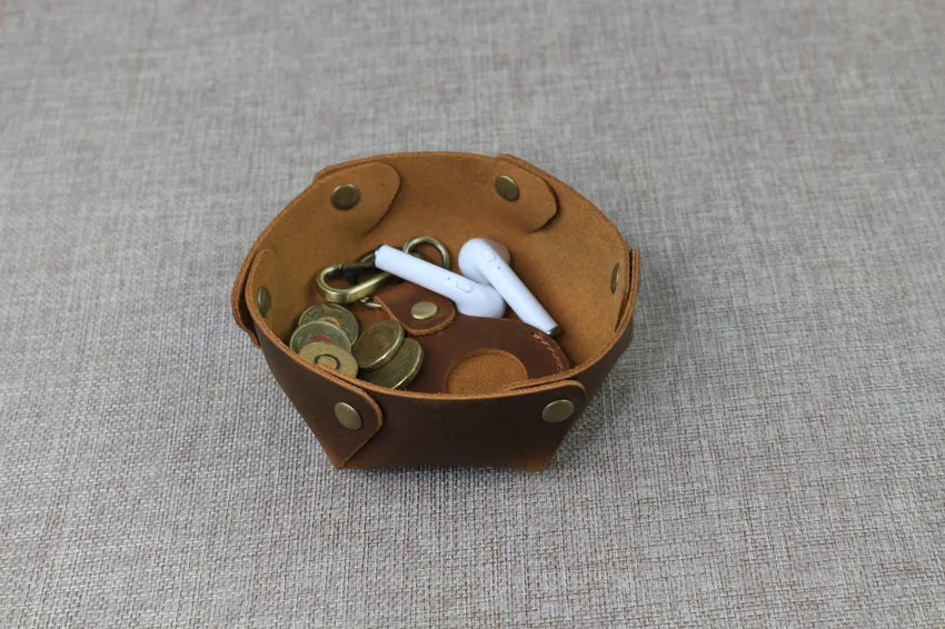 valet desk tray sitting on a desk and storing coins, keys,earbuds in organized way .