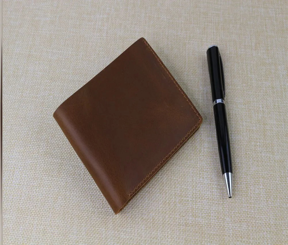 mens wallet leather brown colour sitting on a table with black pen next to it , looking beautiful